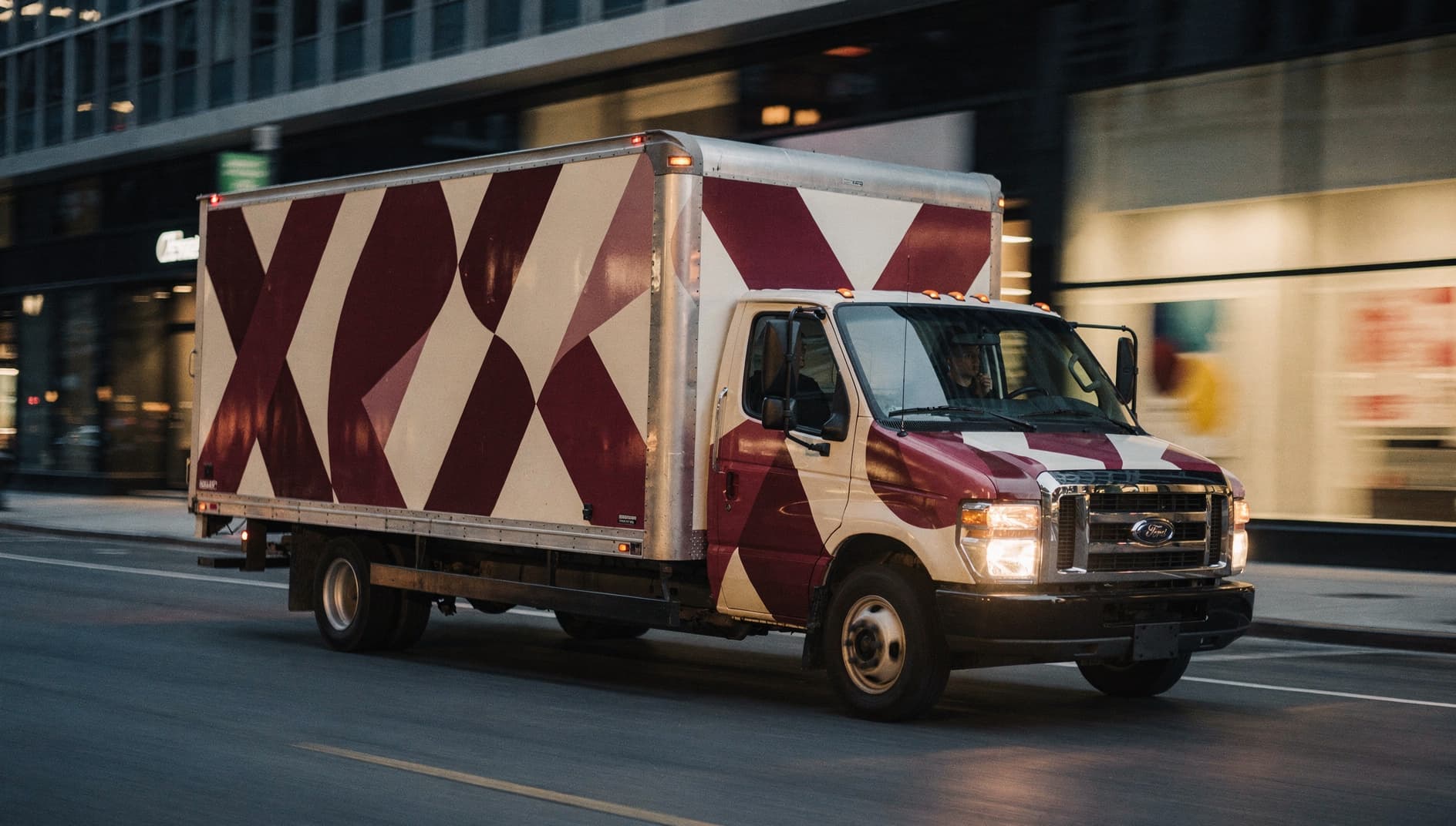 Wrapped box truck driving through downtown at twilight